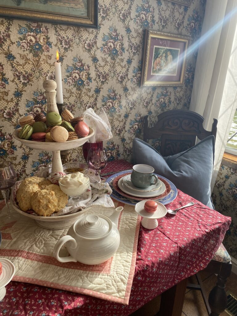 Afternoon tea with tea cups, tea pot, scones, jams, and macaroons