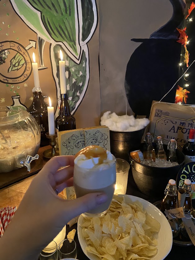 Butterbeer in a tiny glass in front of potions classroom with cauldrons 