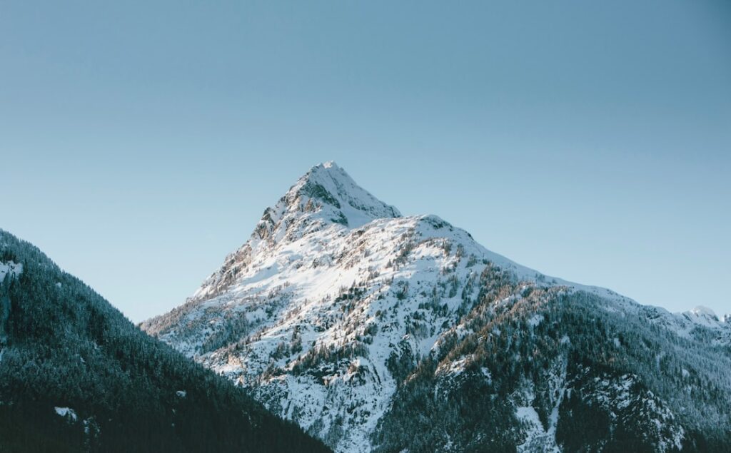 snow covered mountain under blue sky during daytime in Squamish, British Coloumbia